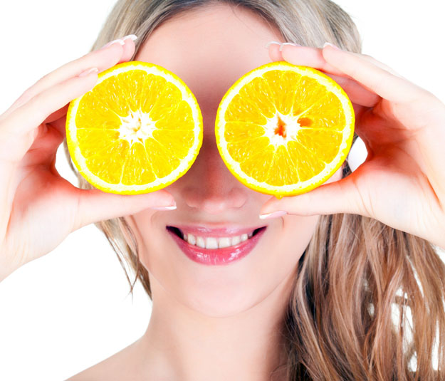Beautiful blond  woman holding orange slices over white