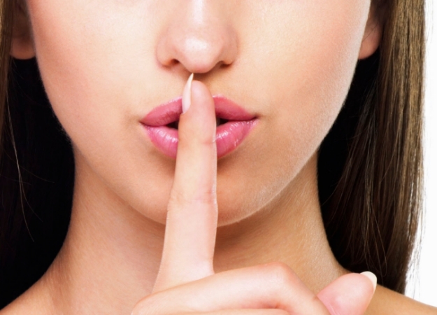 Cropped image of beautiful woman with finger on her lips - copyspace